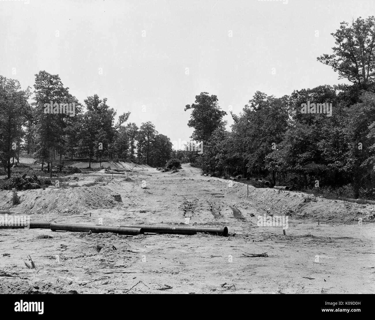 Vue de la terre inégale sur un site de construction pour Baltimore's Northwood Neighbourhood, il y a des tuyaux d'utilité sur le terrain, des arbres bordent la saleté, United States, 1950. Banque D'Images