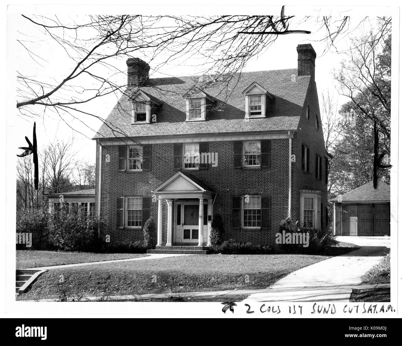 Photo de paysage d'une maison en brique de trois étages, avec des colonnes blanches réunion dans une frise triangulaire à l'avant porte, une allée à l'avant d'un petit hangar ou garage derrière la maison, entourée par des arbres sans feuilles, Roland Park/Guilford, Baltimore, Maryland, 1910. Cette image est tirée d'une série sur la construction et la vente de maisons dans le quartier Roland Park/Guilford de Baltimore, a streetcar suburb et l'une des premières communautés planifiées aux États-Unis. Le quartier a été isolé, et est considéré comme l'un des premiers exemples de l'application de la ségrégation raciale throu Banque D'Images