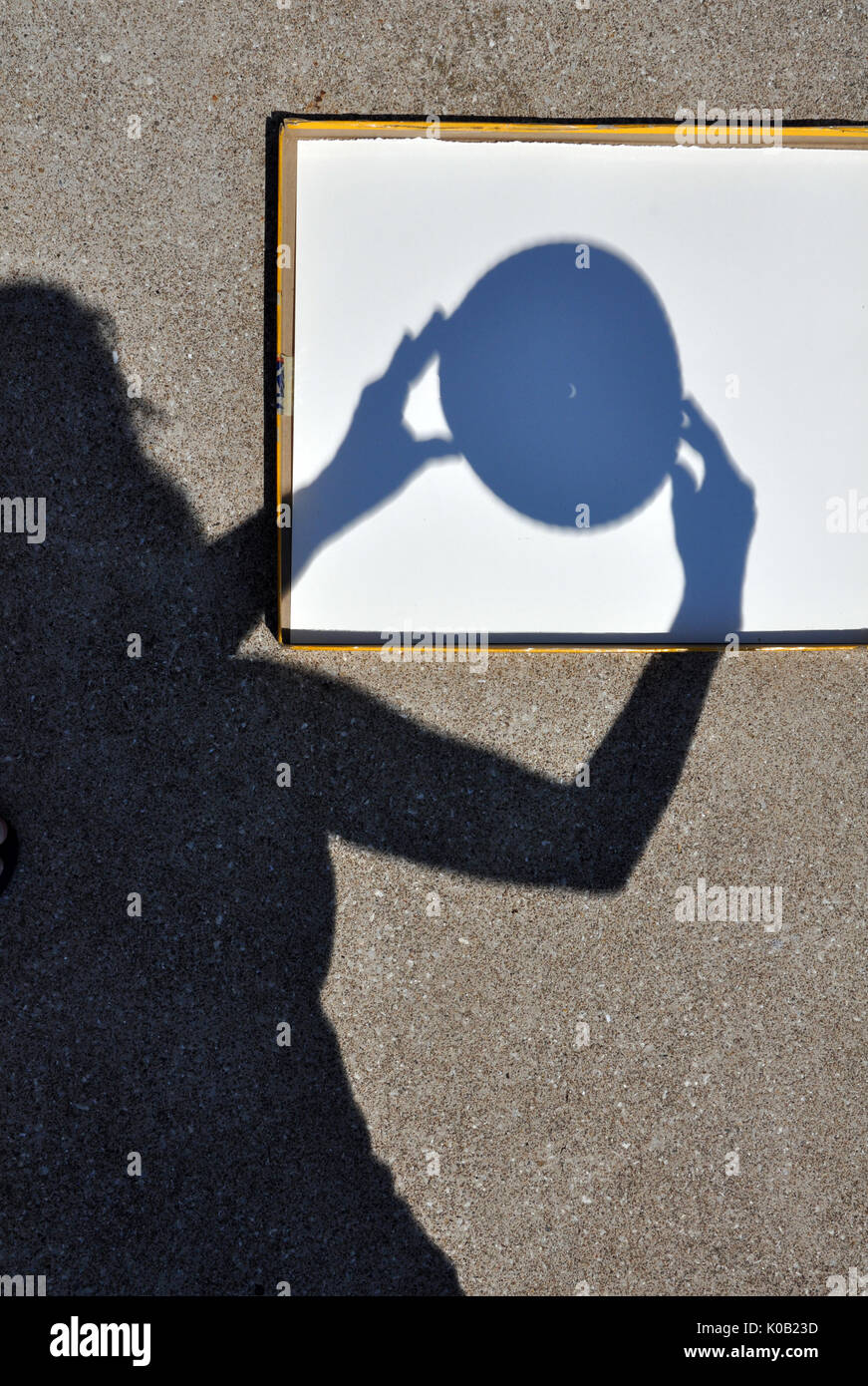 Ombre de jeune femme le positionnement d'un Sténopé capturant le croissant de soleil pendant l'éclipse solaire le 21 août, 2017 Banque D'Images