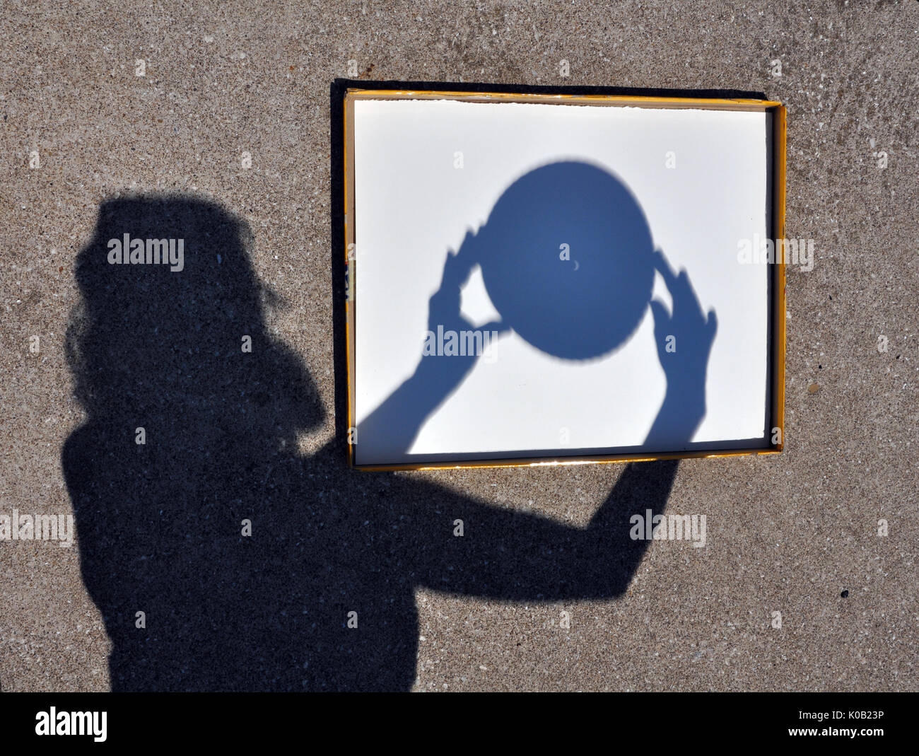 Ombre de Jeune femme tenant un Sténopé capturant le croissant de soleil pendant l'éclipse solaire le 21 août, 2017 Banque D'Images