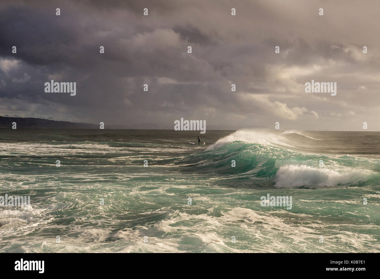 Déferlement des vagues et petit stand up surf paddleboarder, long de corail, Plages du Nord, Sydney, NSW, Australie Banque D'Images