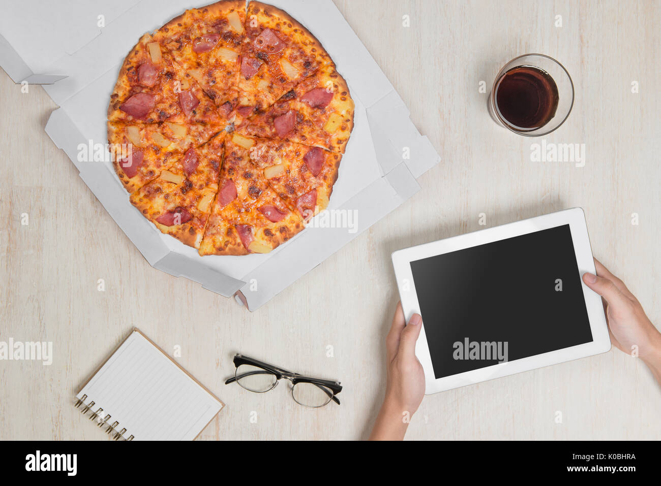 Homme tenant une tablette numérique et pizza savoureuse avec des ingrédients sur la table en bois. Banque D'Images Homme tenant une tablette numérique et pizza savoureuse avec des ingrédients sur la table en bois. Banque D'Images