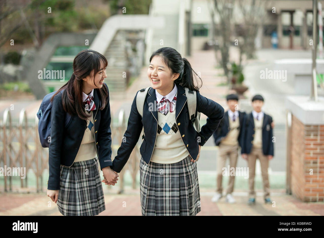 Deux smiling school girls holding hands face à face Banque D'Images