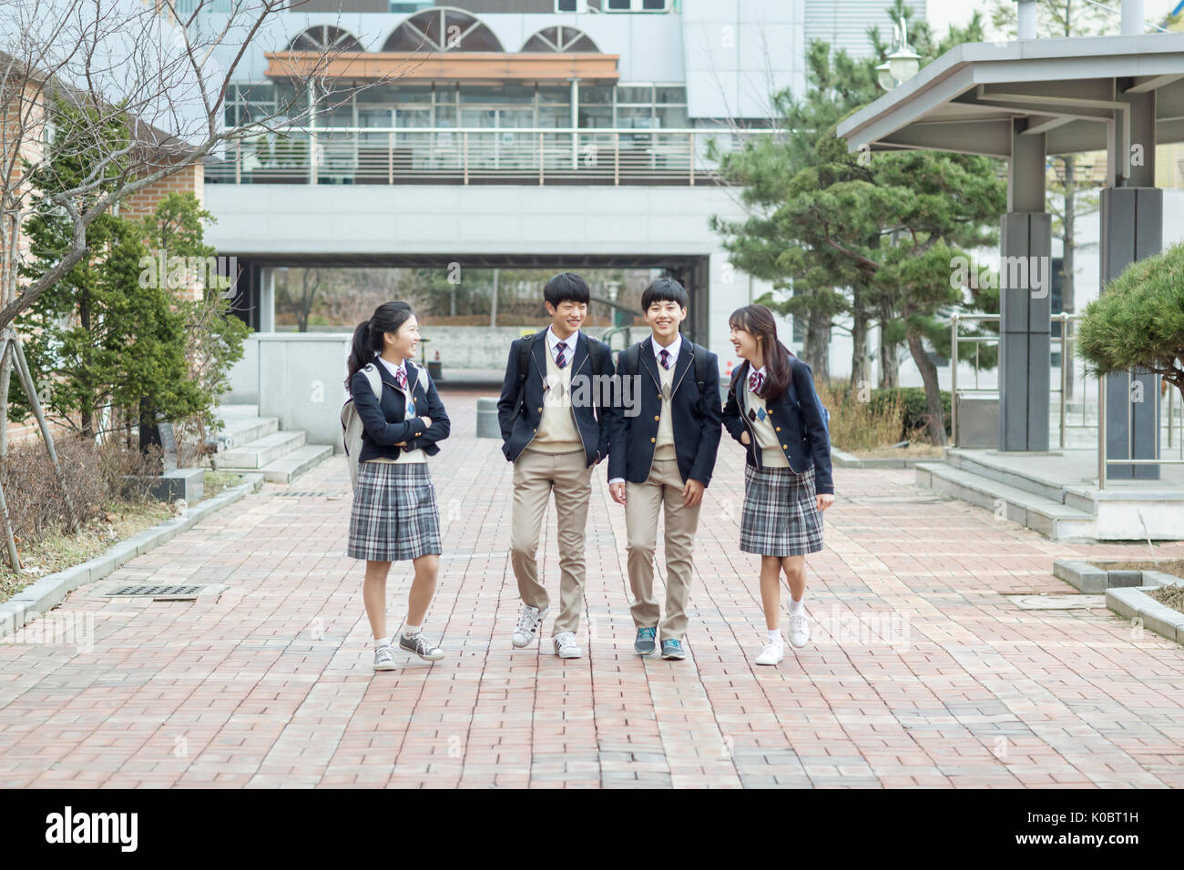 Quatre étudiants de l'école sourire contre leur école à pied Banque D'Images