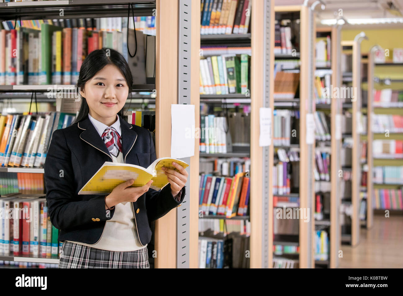 School girl Smiling with book in library Banque D'Images