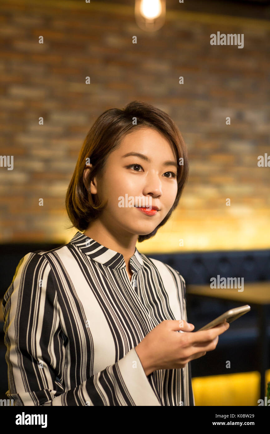 Portrait of smiling businesswoman holding smartphone au get-together Banque D'Images