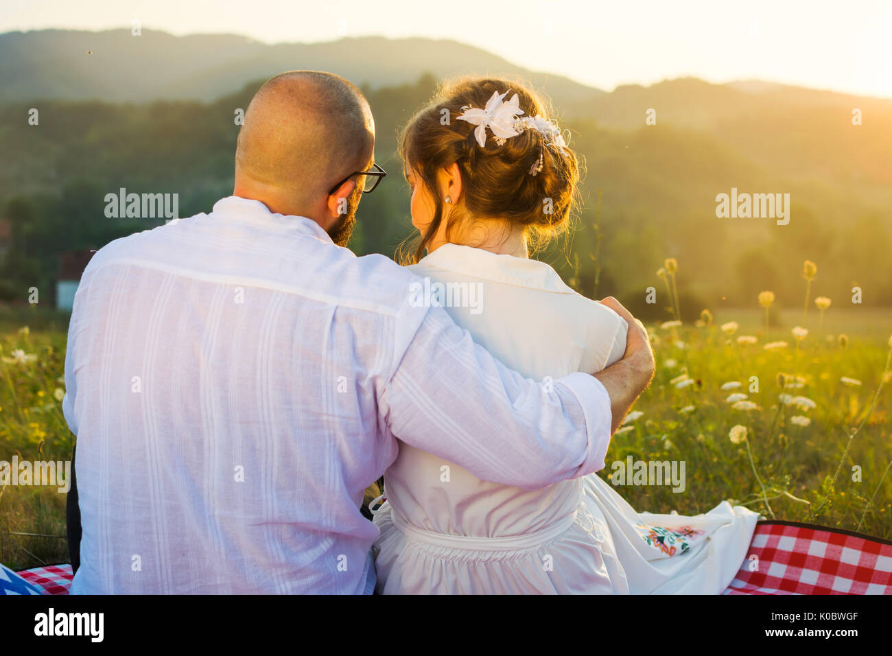 Couple hugging on pique-nique avec vue sur le coucher de soleil romantique Banque D'Images