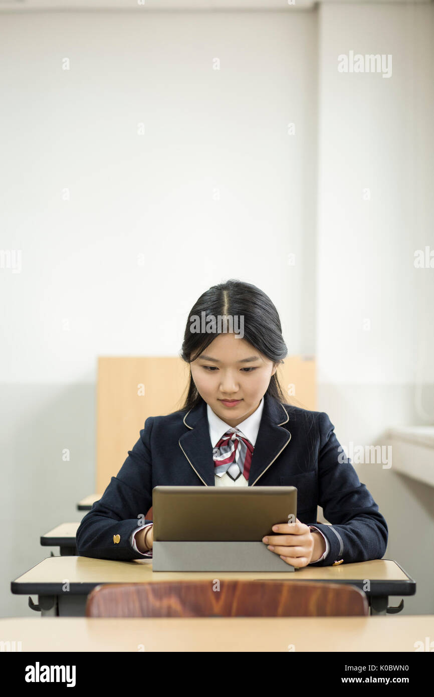 Portrait of smiling school girl with electric tablet in classroom Banque D'Images