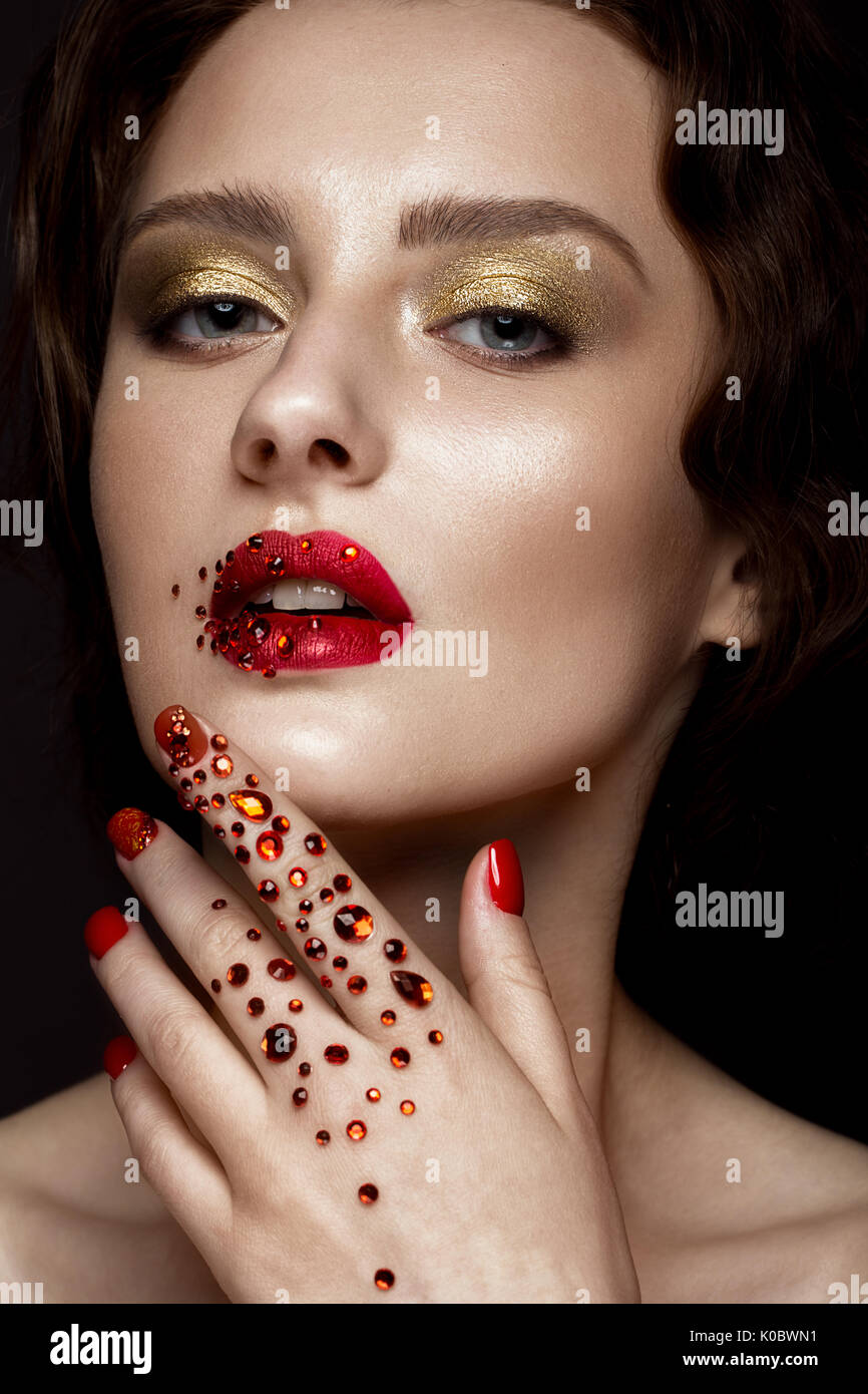 Belle fille avec soir maquillage, lèvres rouge en strass et clous. manucure design beauté visage. Banque D'Images