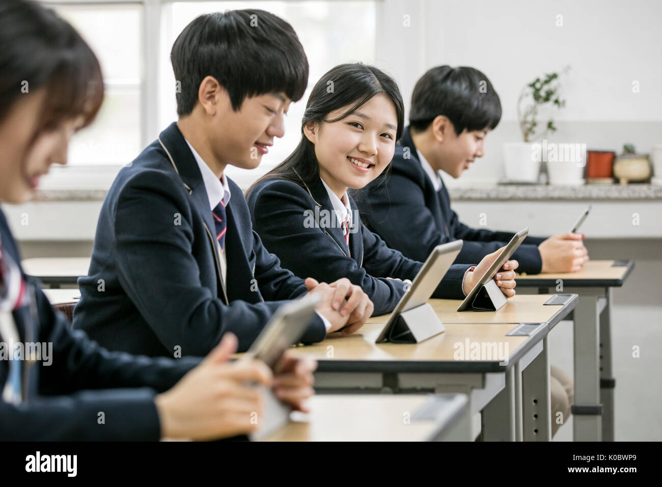 Smiling school girl et ses camarades avec tablettes électriques Banque D'Images