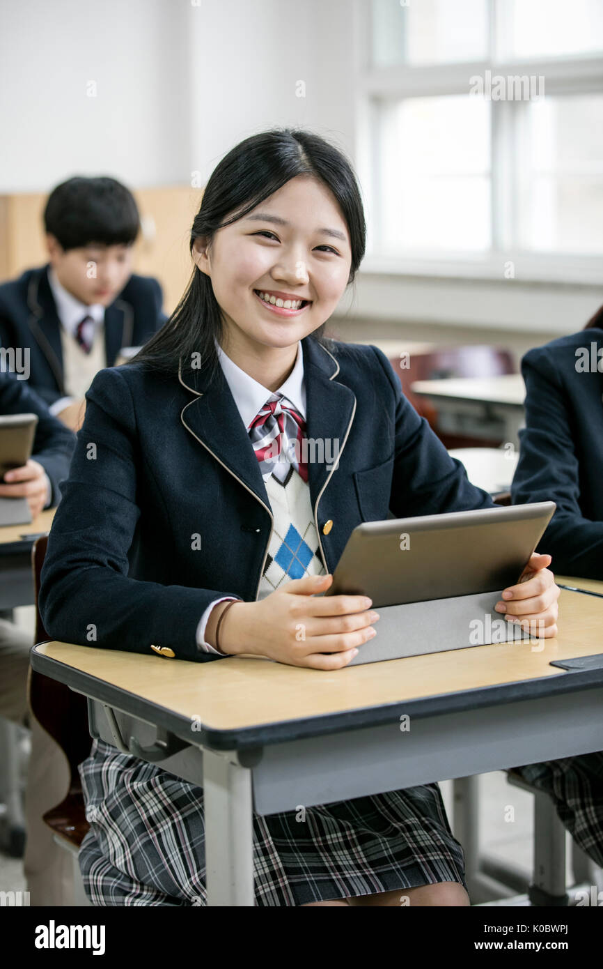 Smiling school girl et ses camarades avec tablettes électriques Banque D'Images