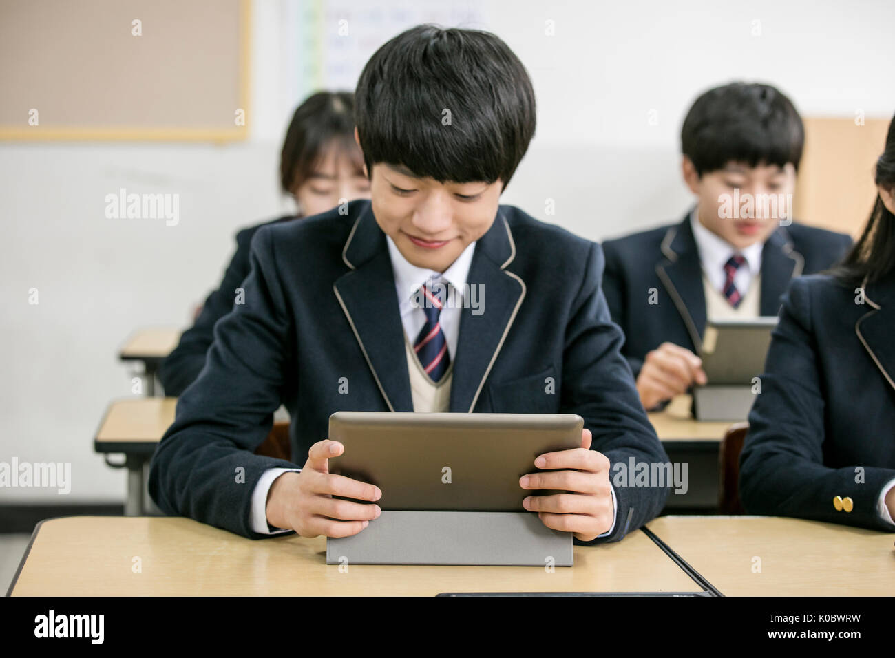 Les élèves de la classe en souriant sur tablettes électriques Banque D'Images