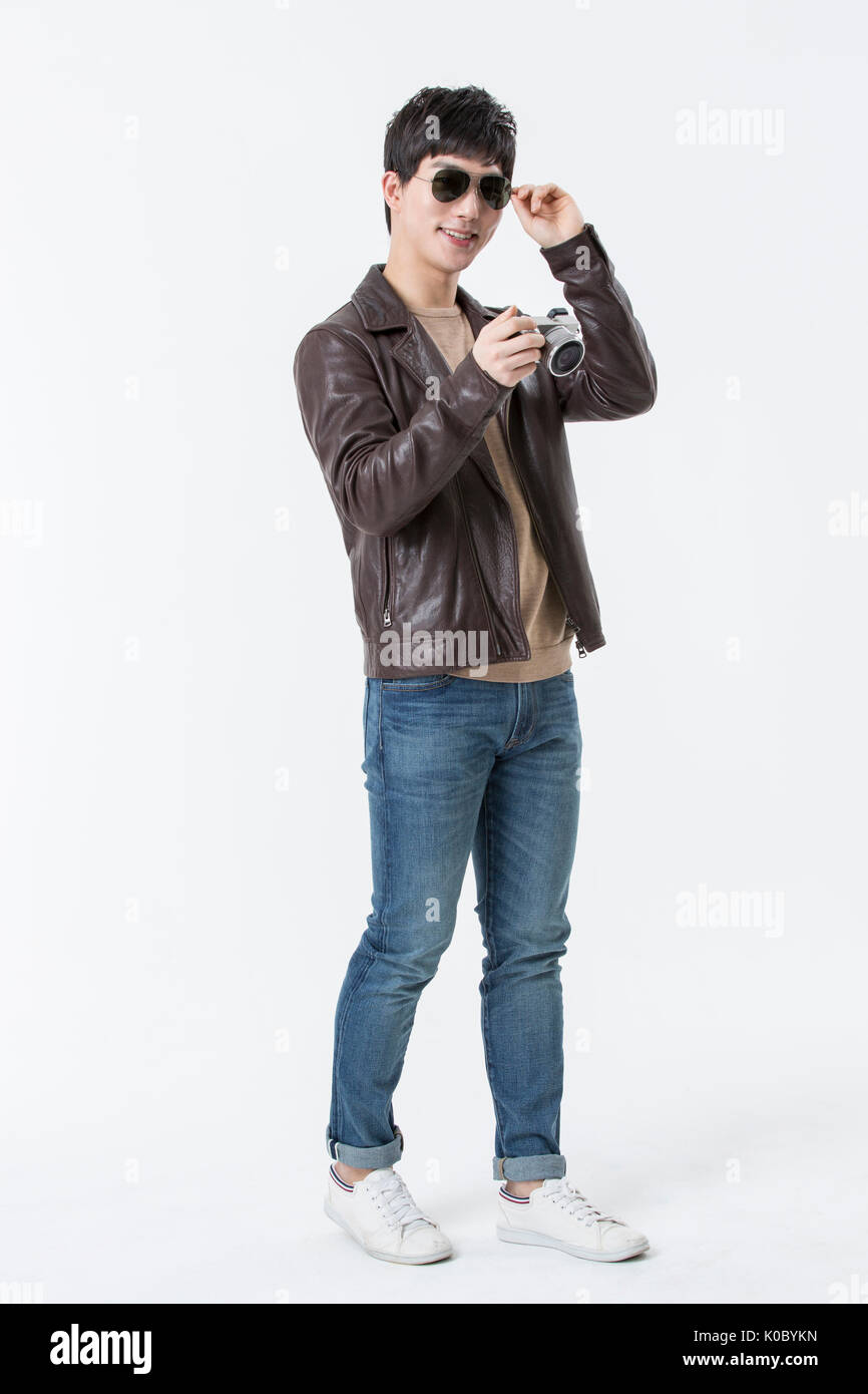 Jeune homme souriant avec des lunettes et blouson de cuir posing holding a camera Banque D'Images