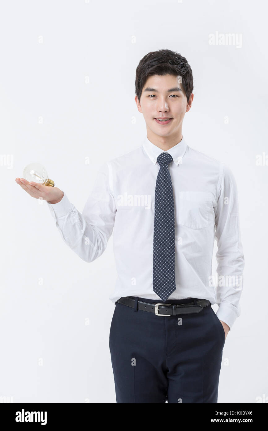 Young smiling confident businessman holding a bulb Banque D'Images