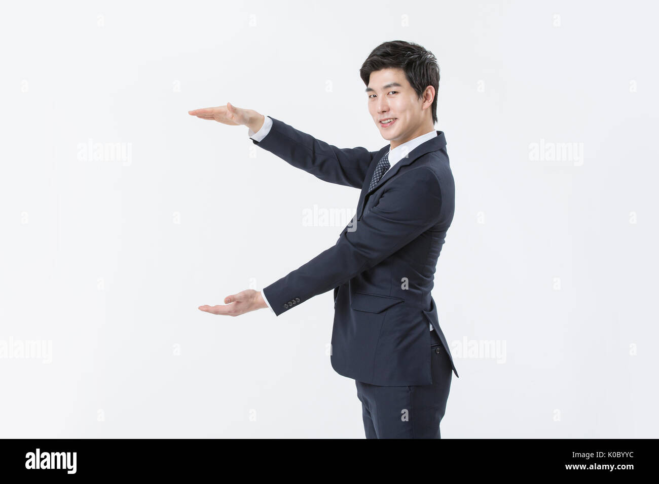 Side view of young smiling businessman in suit holding hands Banque D'Images