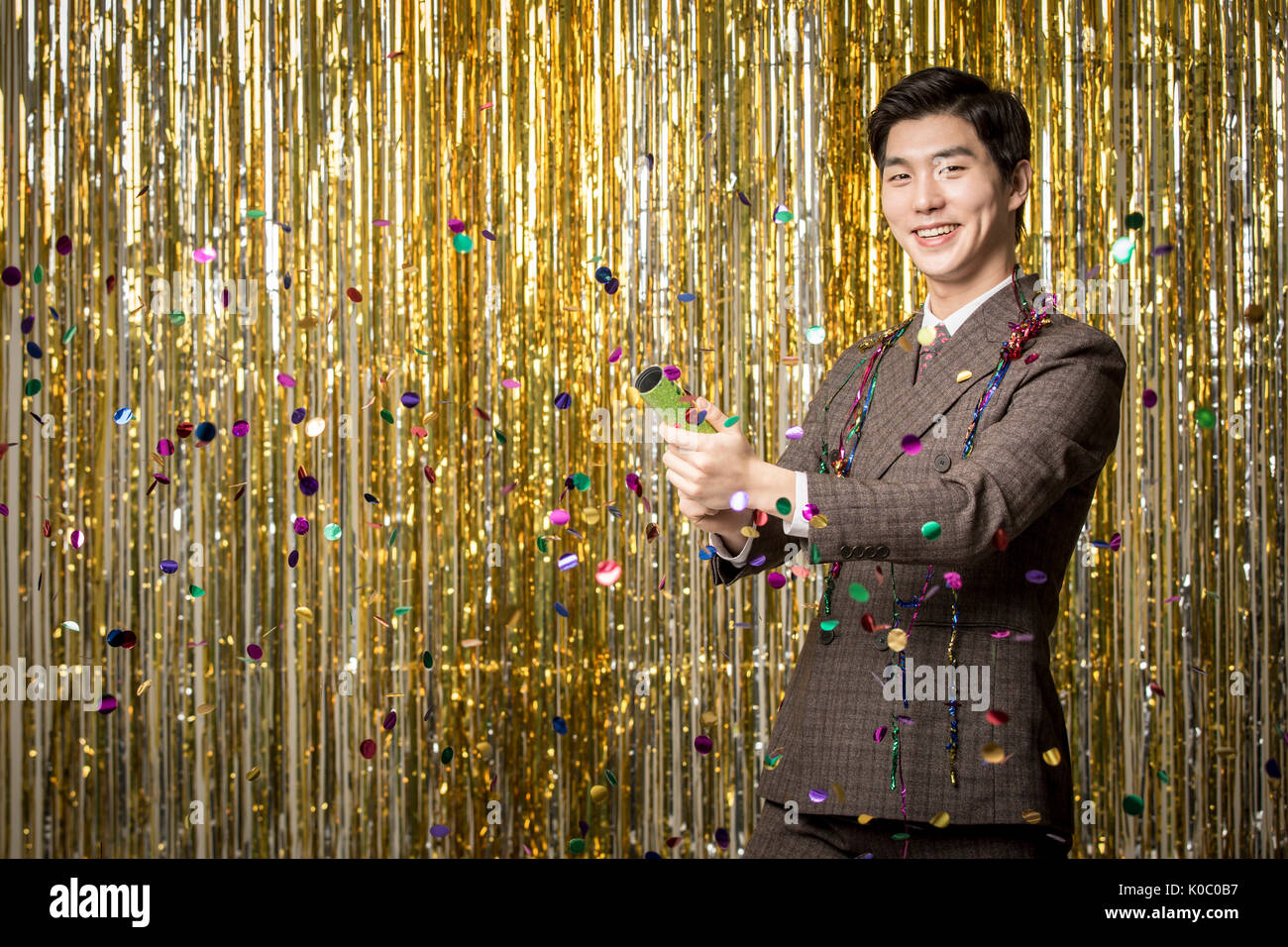 Smiling Young man in suit la mise en place d'un pétard at party Banque D'Images