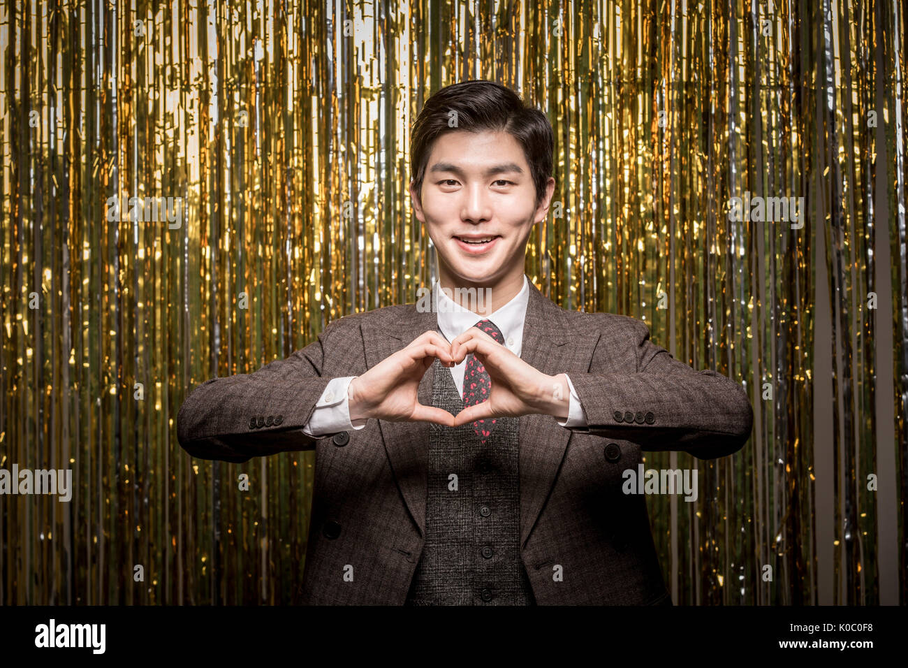 Portrait of young smiling man making coeur avec les doigts Banque D'Images