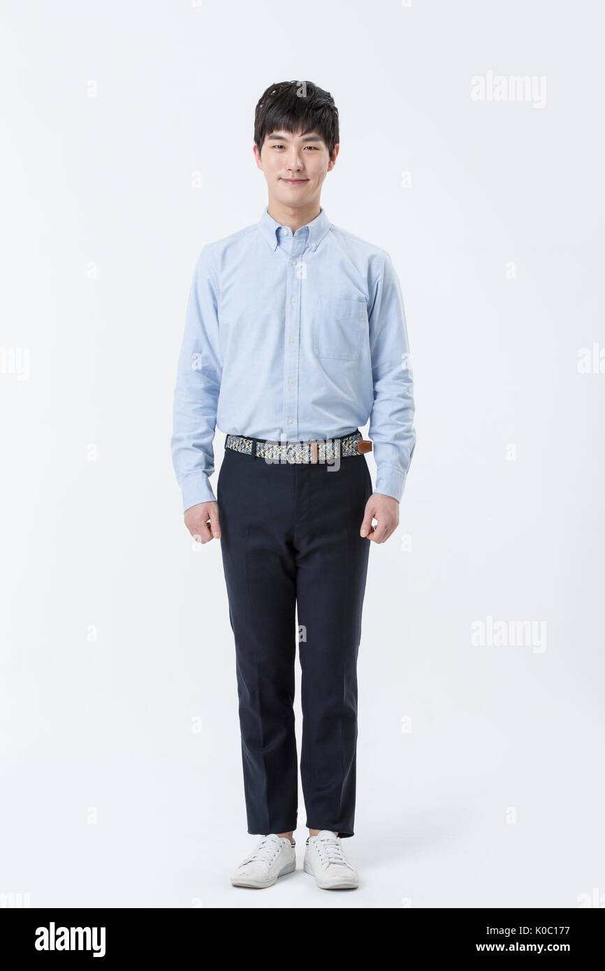 Jeune homme souriant en chemise, pantalon et chaussures blanc debout Banque D'Images