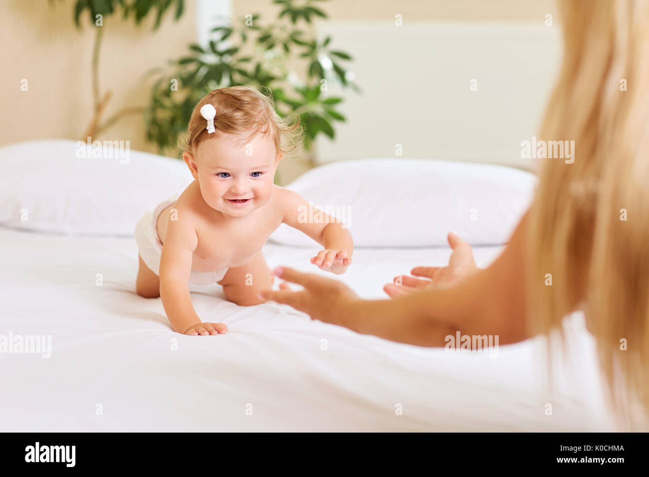 Bébé Enfant joue lentement sur le lit de la mère à l'intérieur Banque D'Images