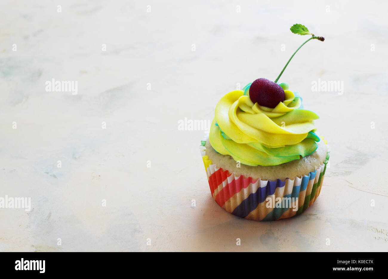 Cupcake à la vanille avec un plafond de fromage à la crème de couleur cerise avec un fond clair Banque D'Images