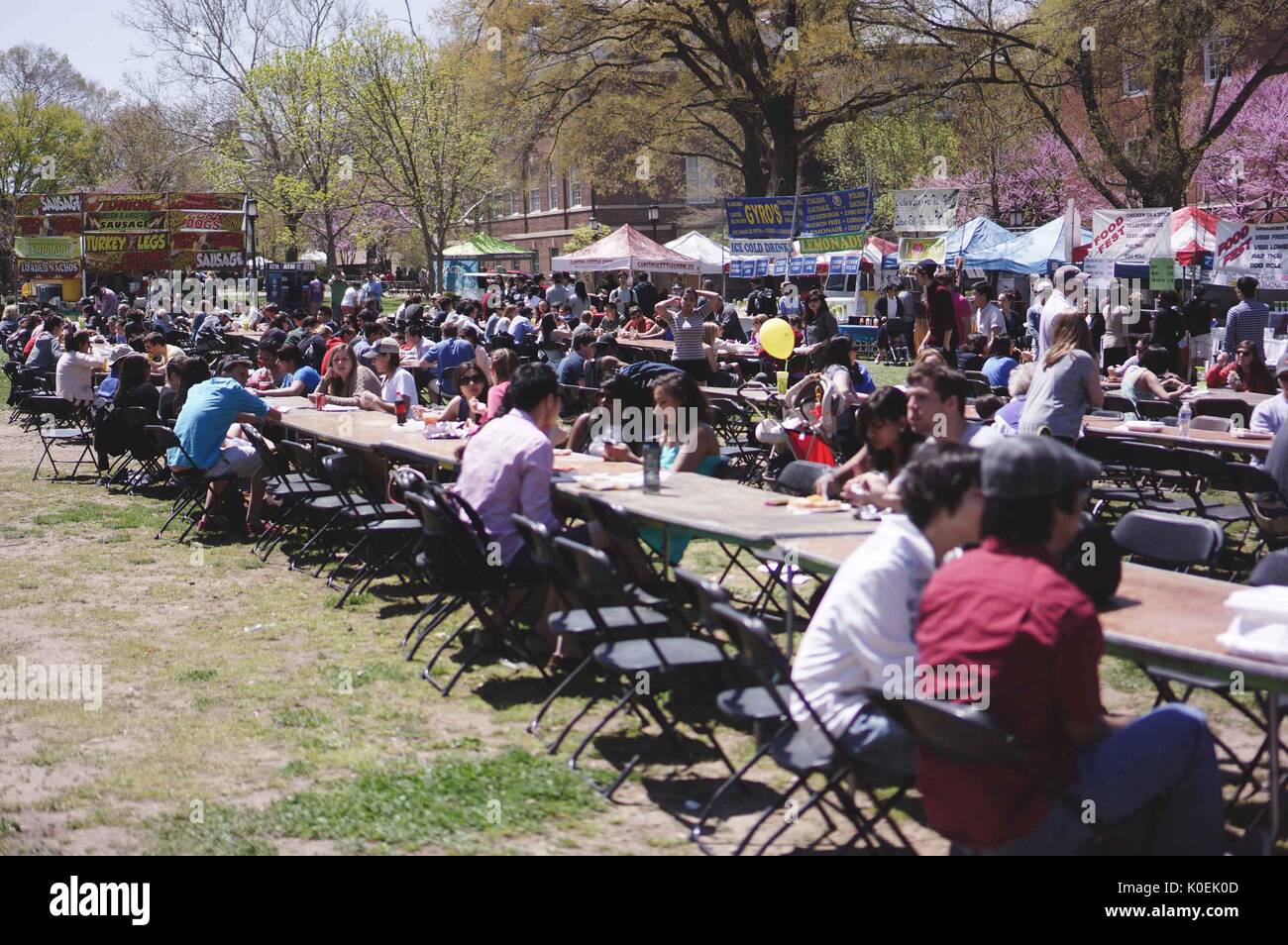 Les étudiants et membres de l'université Johns Hopkins de Baltimore et les collectivités ont à table, manger et socialiser comme des stands de restauration les entourent, au cours de foire de printemps, un festival annuel avec musique, nourriture, shopping, et bien plus qu'a lieu chaque printemps sur l'homewood campus de l'université Johns Hopkins de Baltimore, Maryland. 2014. courtesy eric chen. Banque D'Images