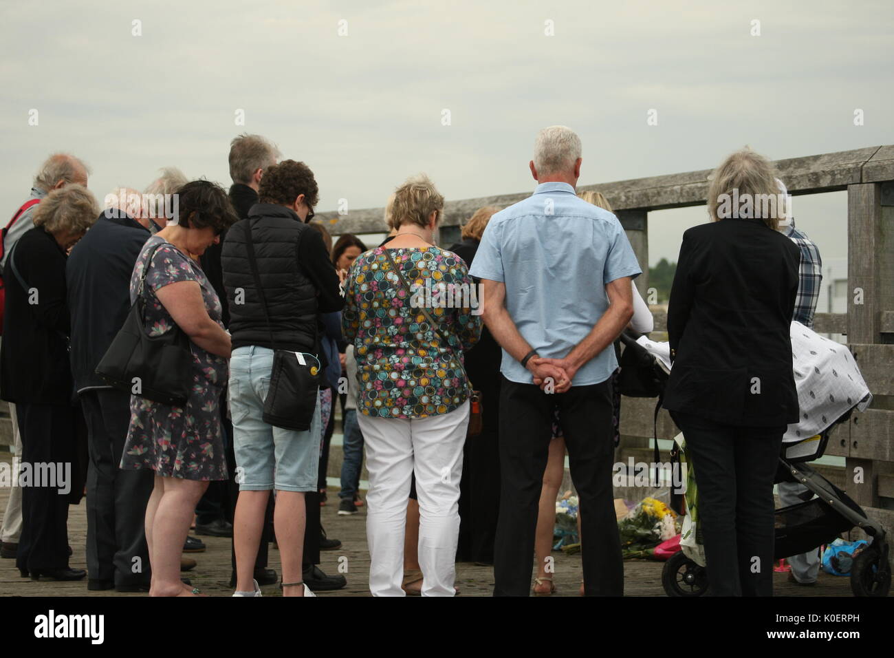 Shoreham-by-Sea, Sussex, UK, 22 août 2017. Sur le 2ème anniversaire de la catastrophe à Shoreham Airshow, les familles et les autres se sont réunis pour se rappeler les 11 hommes qui sont morts. Le désastre qui s'est produit lorsqu'un jet Hawker Hunter s'est écrasé dans une rue animée au cours de la jonction de l'aéronautique, les deux familles ont tenu une minute de silence sur un pont en bois sur la rivière Adur fermer le site de l'accident. Les familles baissent la tête en silence. Roland Ravenhill/Alamy Live News Banque D'Images