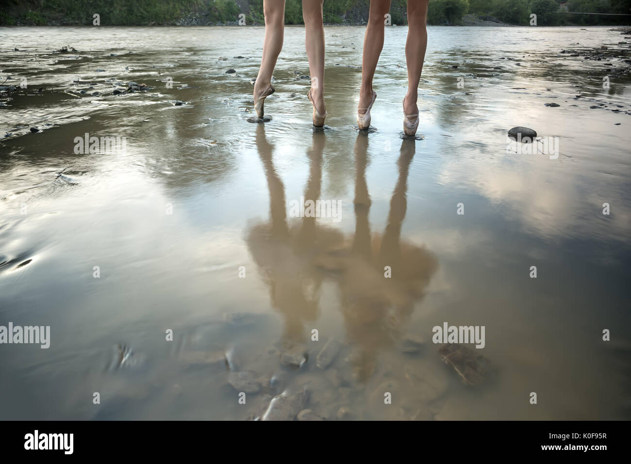 Deux ballerines se tenir sur pointes dans la rivière peu profonde à l'extérieur. Ils reflètent les organismes à la surface de l'eau. L'horizontale. Banque D'Images