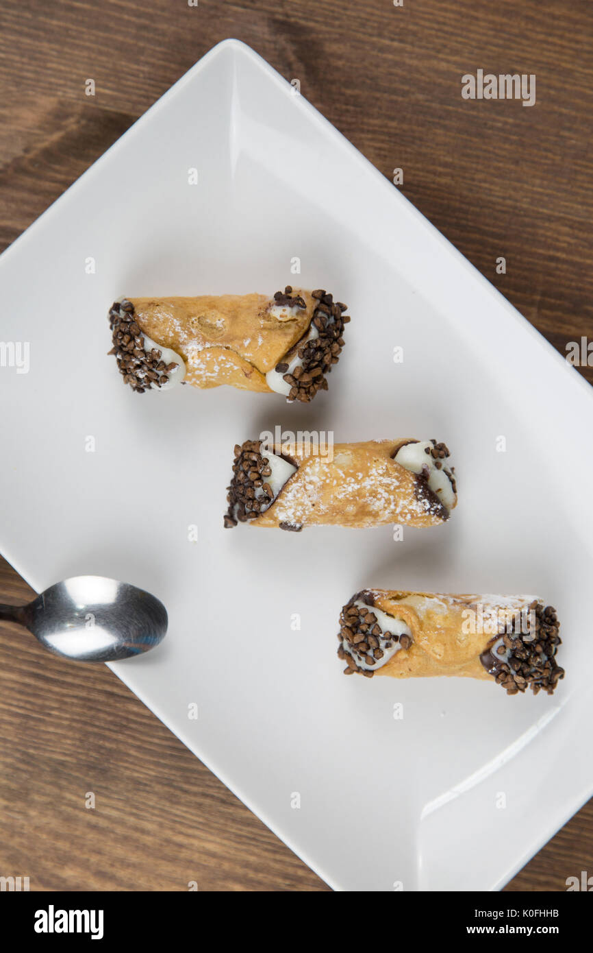 Cannoli siciliens sur blanc plat sur table en bois Banque D'Images