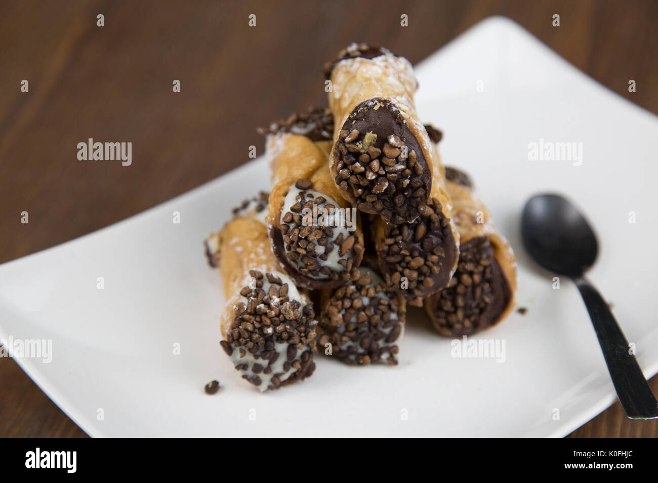 Cannoli siciliens sur blanc plat sur table en bois Banque D'Images