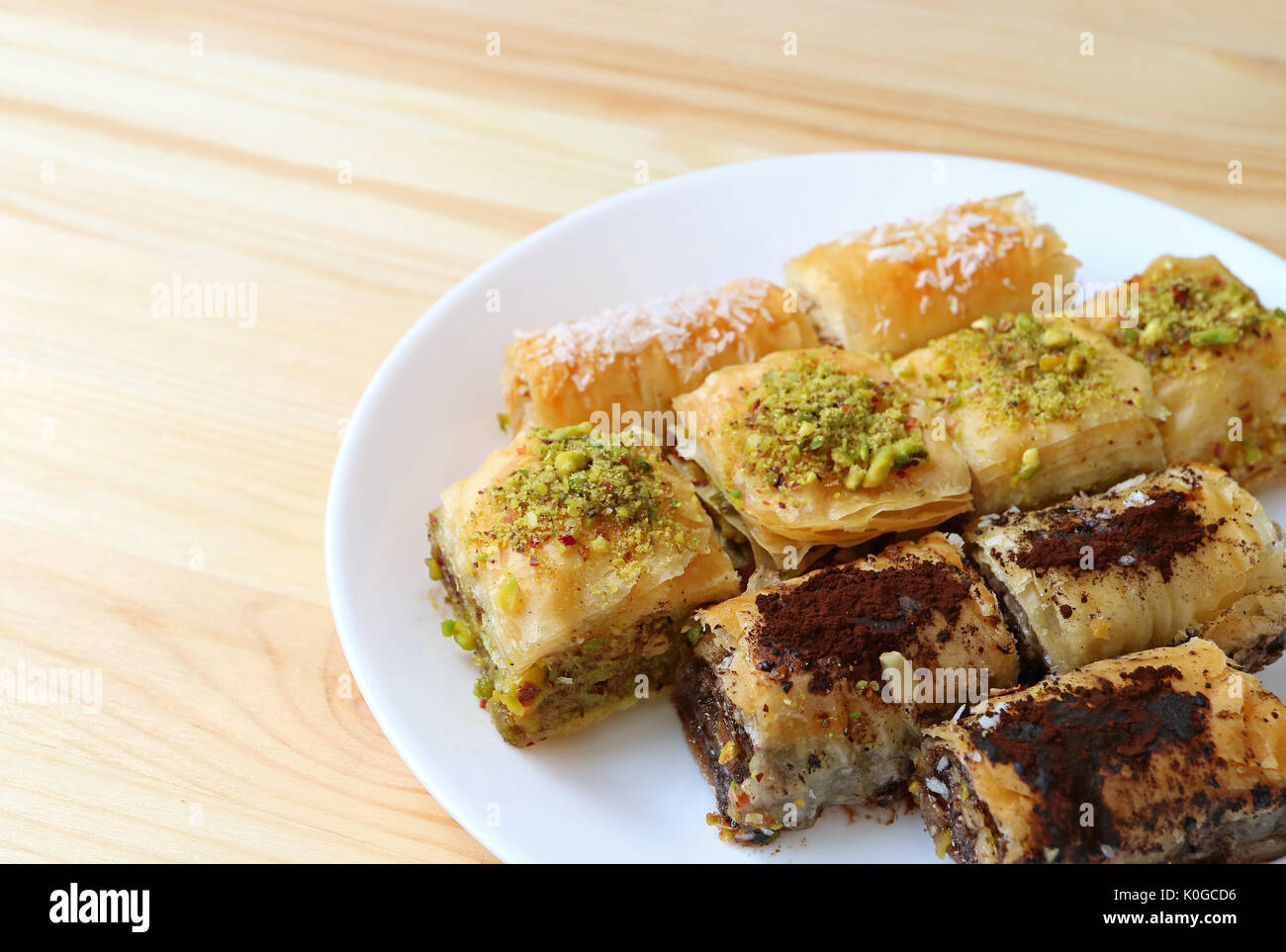 De nombreux types de Baklava pâtisseries sur plaque blanche servi sur une table en bois, avec de l'espace libre pour le texte et la conception Banque D'Images