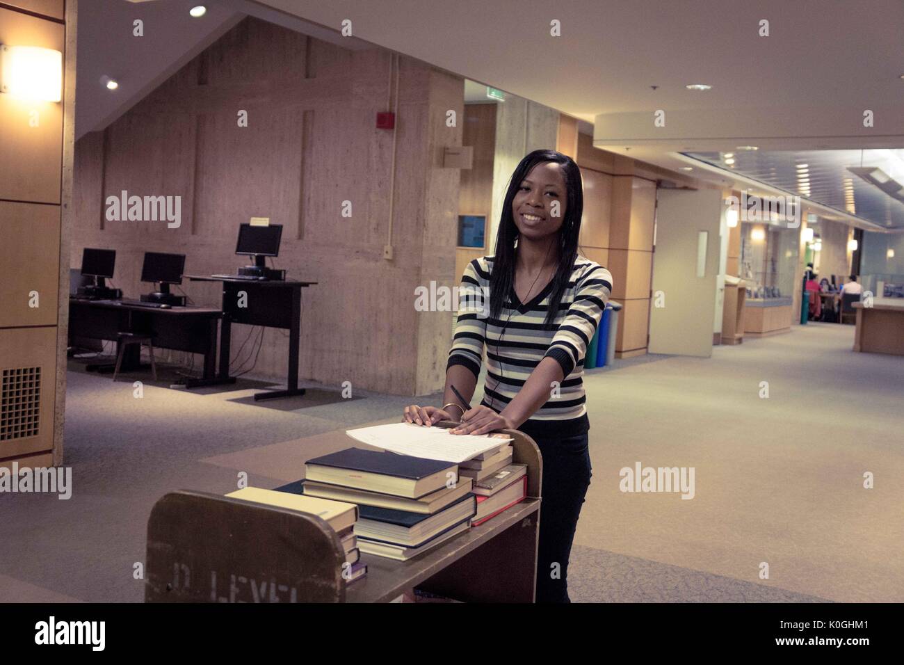 Un employé de la Milton S. Eisenhower Library pousse un chariot plein de livres sur le niveau M (principal) de la bibliothèque, sur le campus Homewood de l'Université Johns Hopkins à Baltimore, Maryland, 2015. Avec la permission d'Eric Chen. Banque D'Images