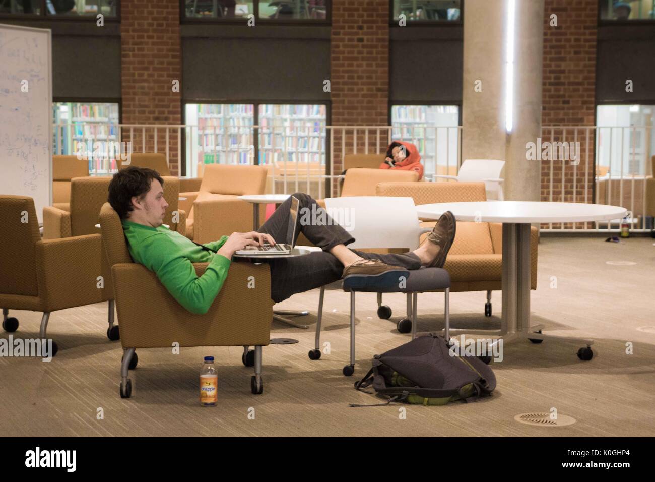 Un étudiant avec ses pieds vers le haut des études sur son ordinateur portable tandis que son homologue nap à proximité, au rez-de-chaussée de Brody Learning Commons, un espace d'étude interactif/collaboratif et une bibliothèque sur le campus Homewood de l'Université Johns Hopkins à Baltimore, Maryland, 2013. Avec la permission d'Eric Chen. Banque D'Images
