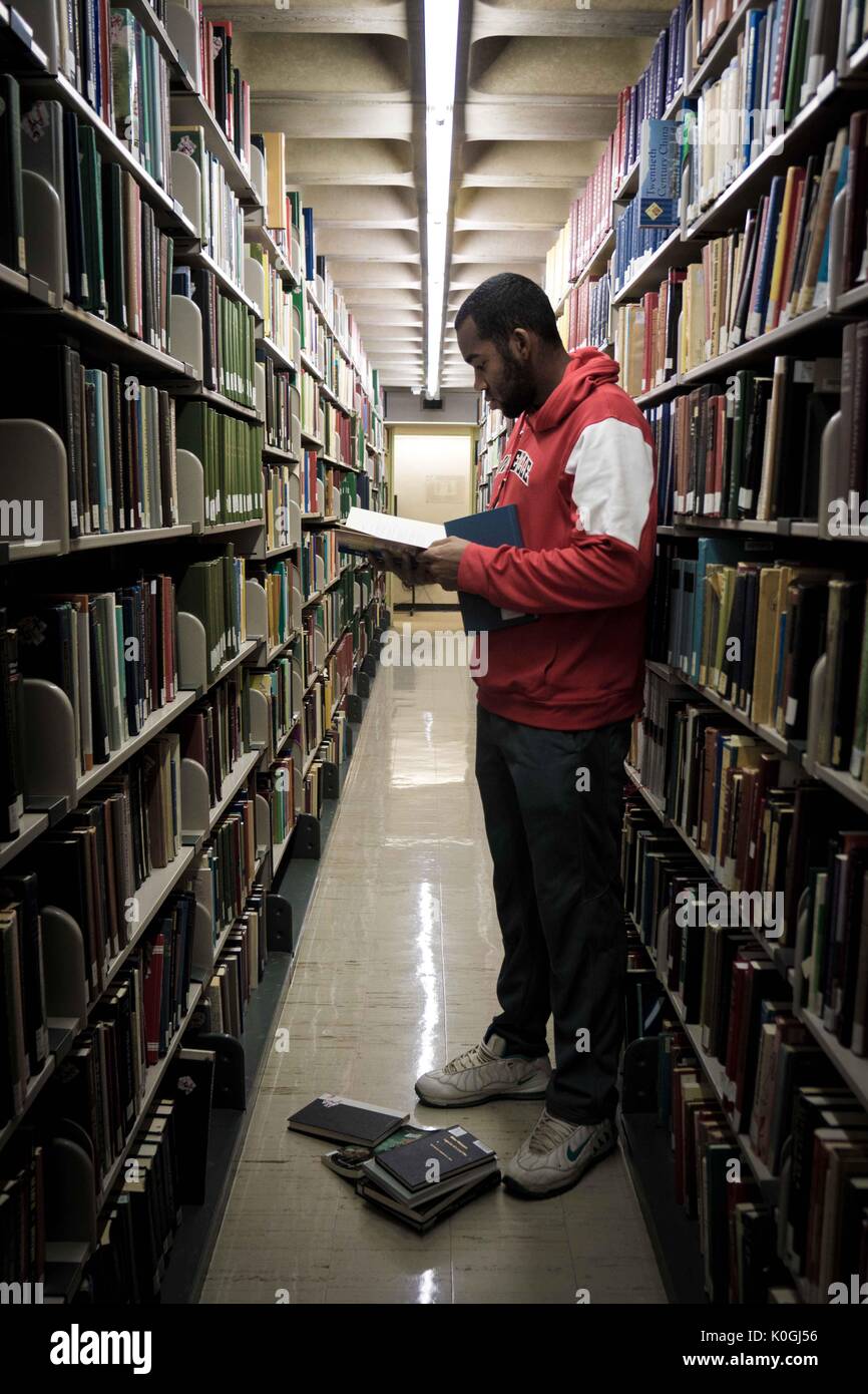 Un étudiant se tient et lit un livre parmi les piles de la bibliothèque Milton S. Eisenhower sur le campus Homewood de l'Université Johns Hopkins à Baltimore, Maryland, 2015. Avec la permission d'Eric Chen. Banque D'Images