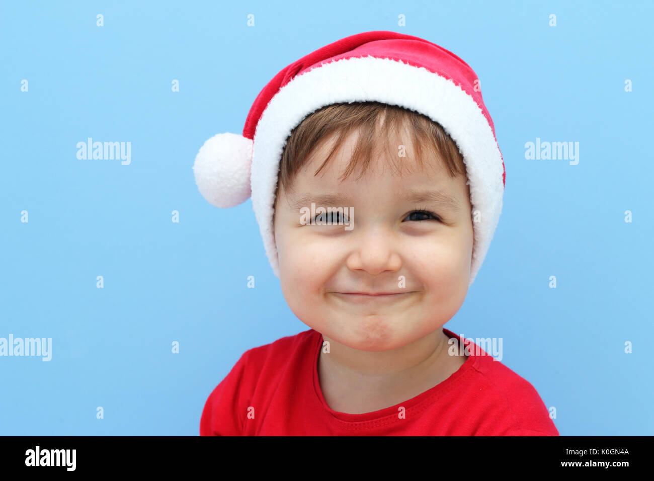 Heureux petit enfant habillé avec un costume de Père Noël dans un fond bleu Banque D'Images