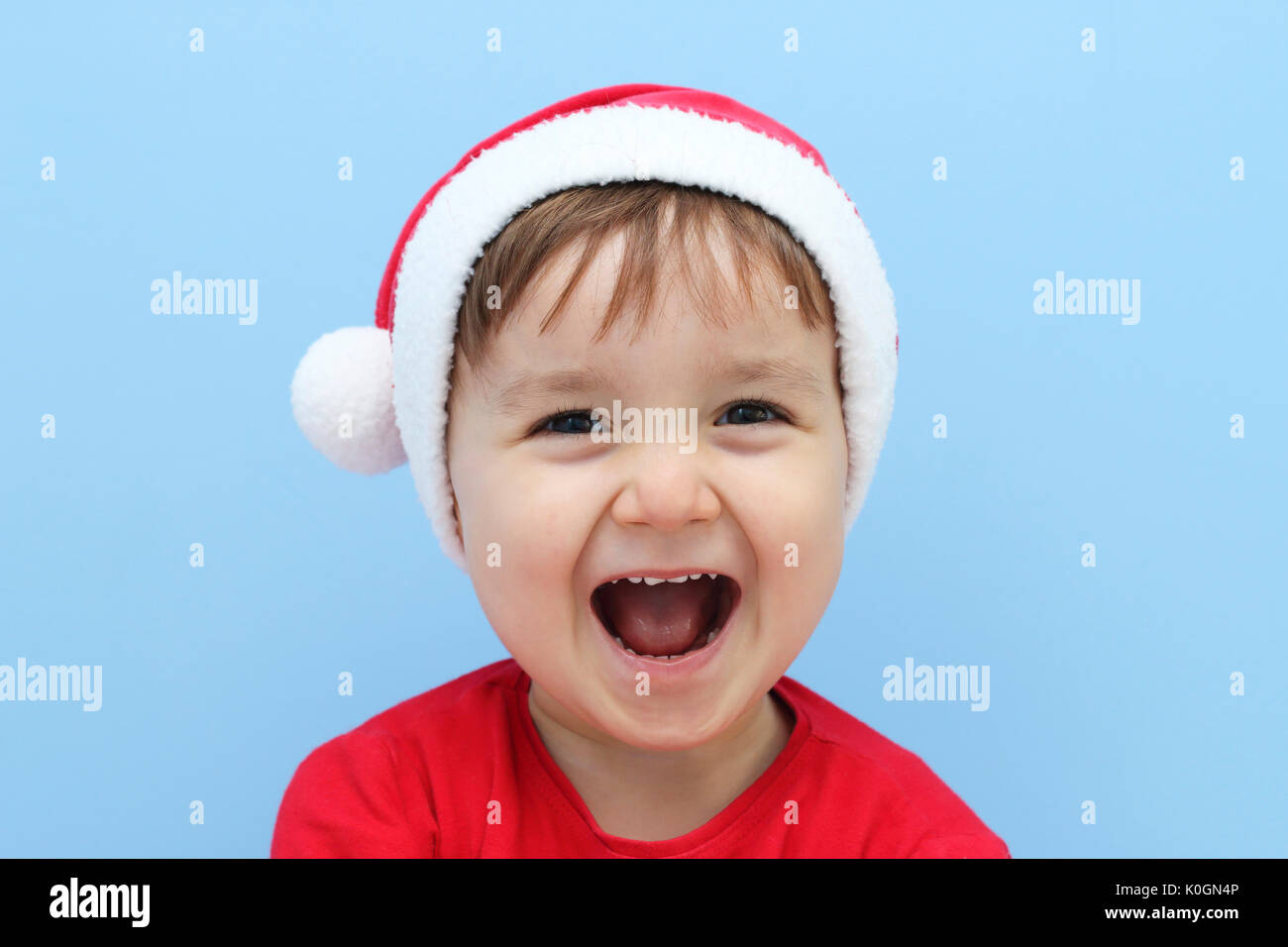 Heureux petit enfant habillé avec un costume de Père Noël dans un fond bleu Banque D'Images