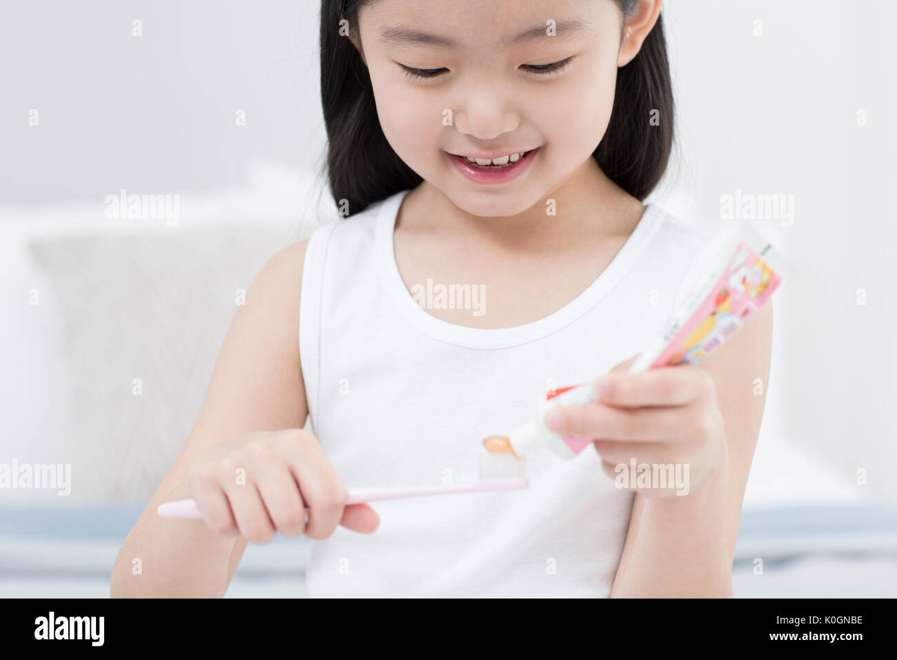 Portrait of smiling girl squeezing dentifrice sur une brosse à dents Banque D'Images