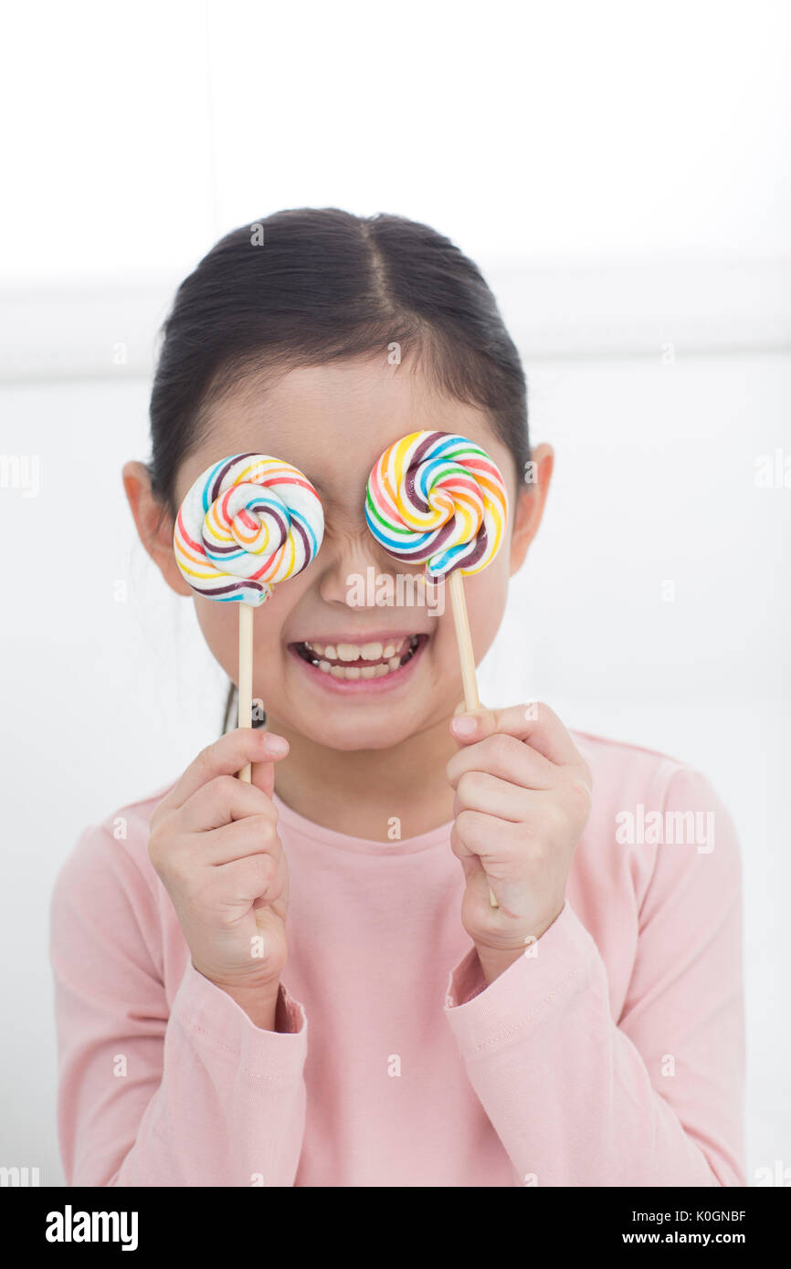 Portrait of smiling girl couvrant ses yeux avec lollipops Banque D'Images