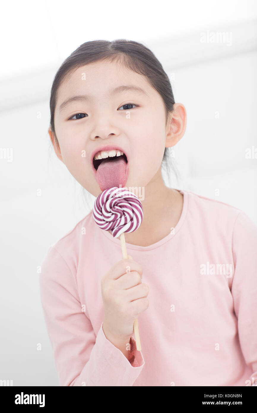 Portrait of smiling girl licking lollipop Banque D'Images