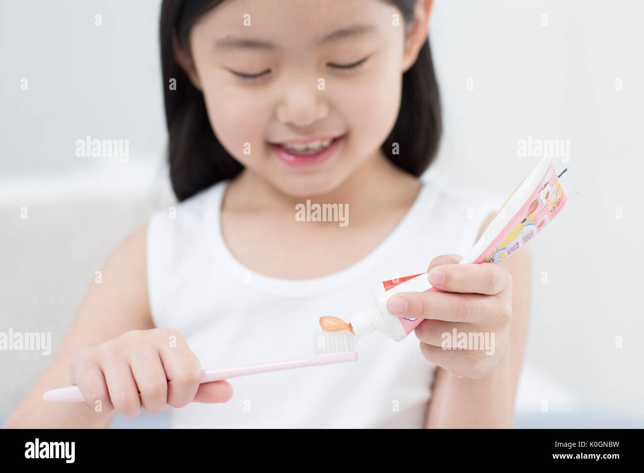 Portrait of smiling girl squeezing dentifrice sur une brosse à dents Banque D'Images