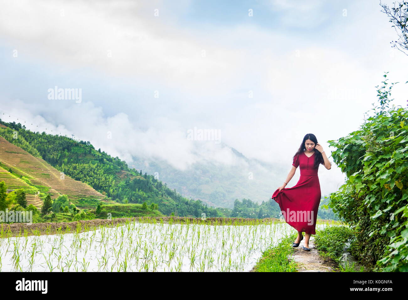 Girl in red dress marcher par la terrasse de riz au-dessus des nuages Banque D'Images