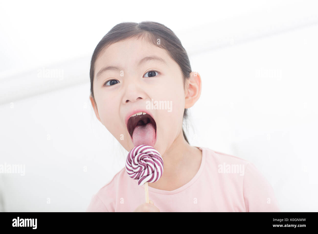 Portrait of smiling girl licking lollipop Banque D'Images