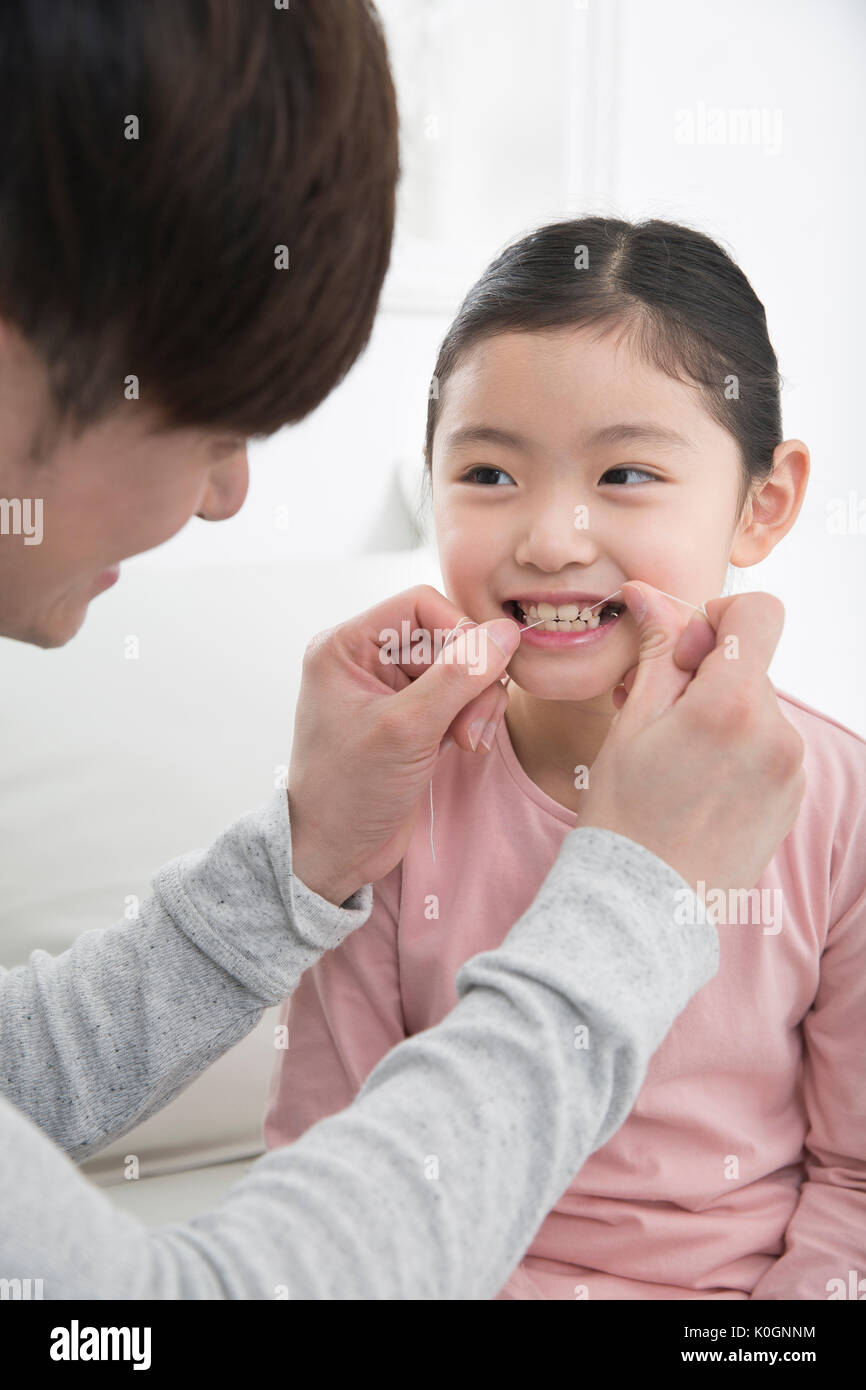 Portrait of smiling père et fille à l'aide du fil dentaire Banque D'Images