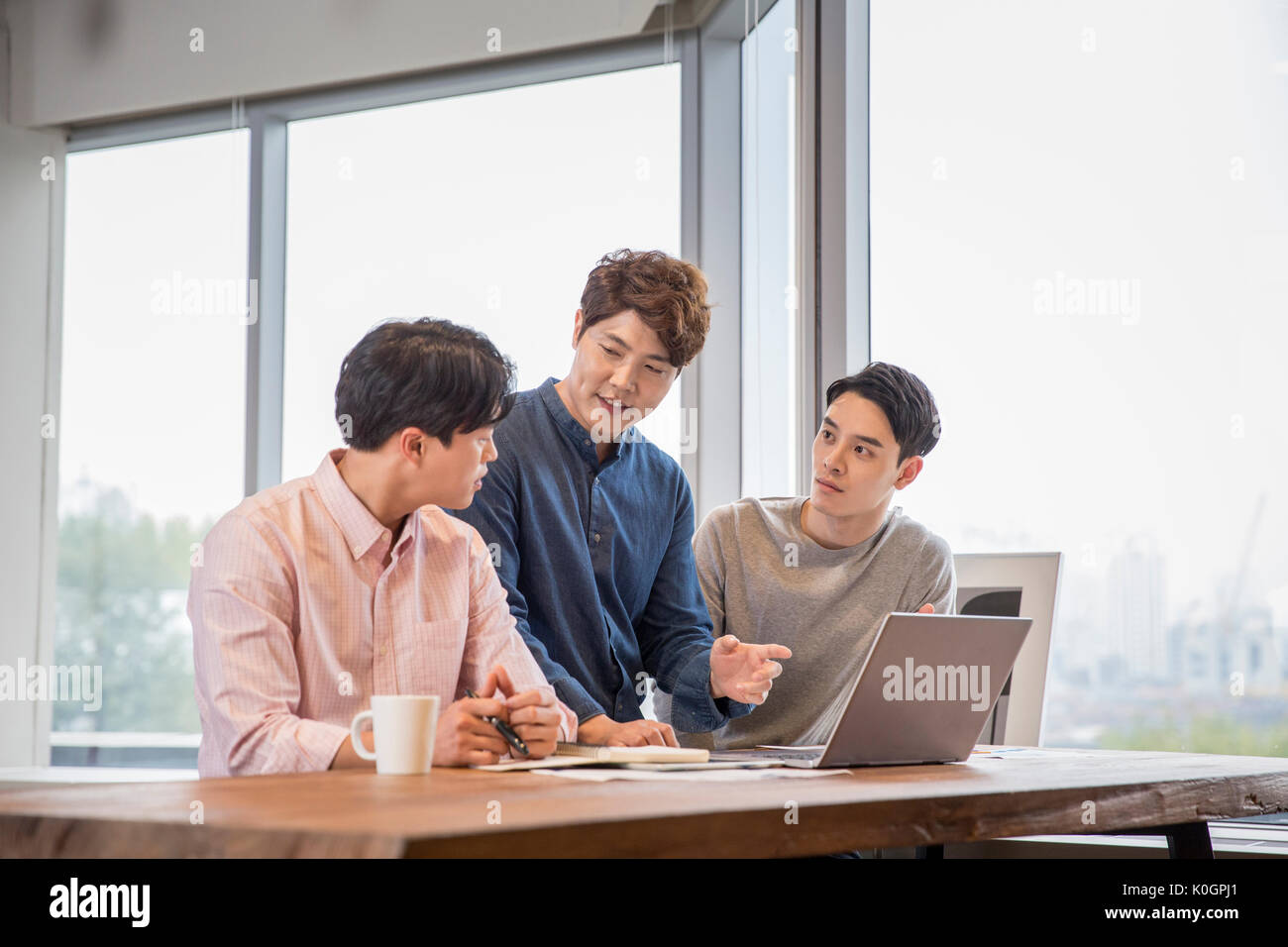 Trois smiling businessmen having a meeting at office Banque D'Images