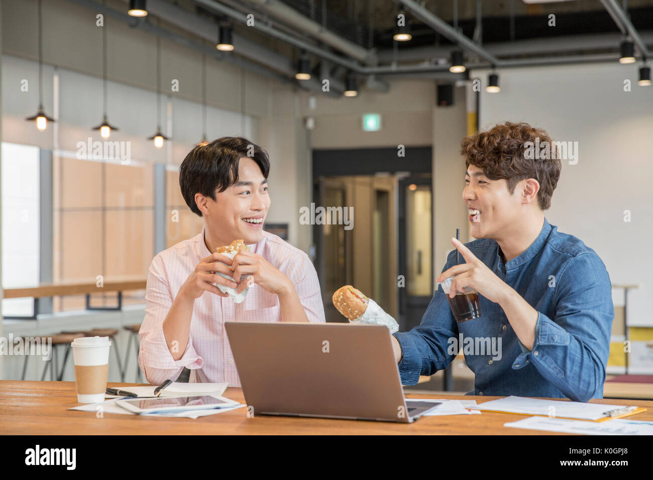 Portrait of two smiling businessmen having a parler de manger des sandwichs au cafétéria Banque D'Images