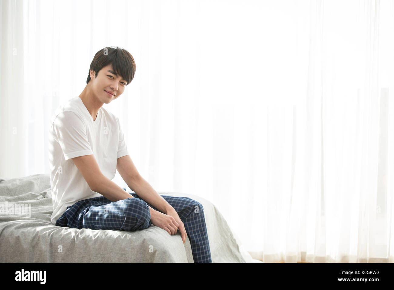 Homme seul Smiling sitting on bed Banque D'Images