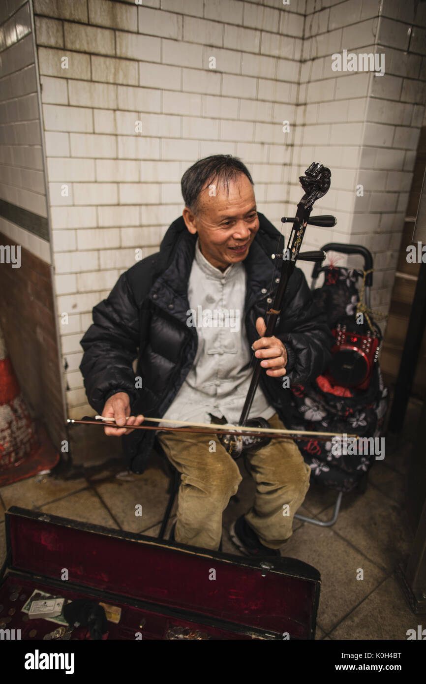 New York, États-Unis d'Amérique - le 9 avril 2017. Un musicien de rue est la lecture de la "Erhu" au milieu de la station de métro. Banque D'Images