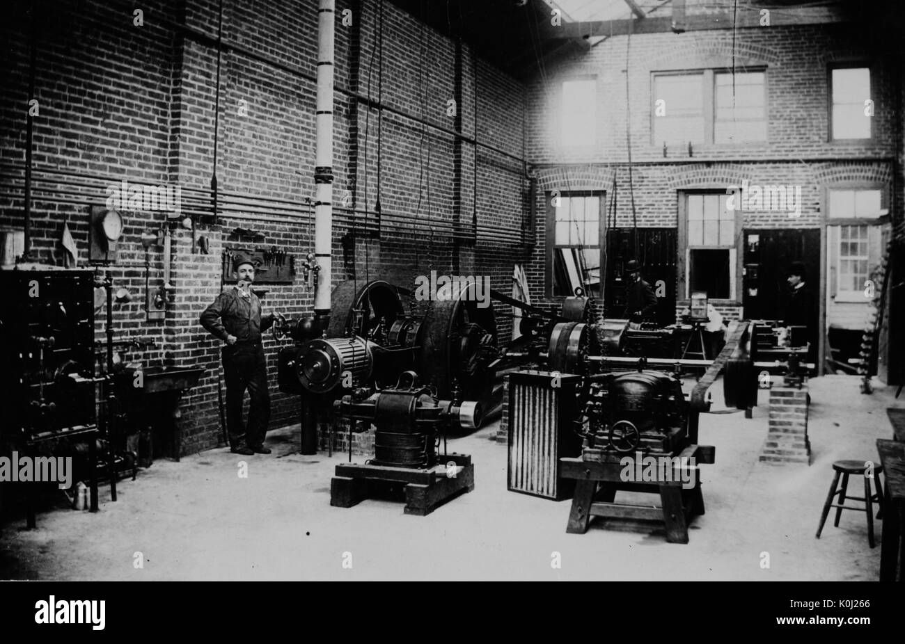L'intérieur d'une centrale électrique à l'université Johns Hopkins, représentant un homme qui tend à une pièce d'équipement et diverses autres machines. 1900. Banque D'Images