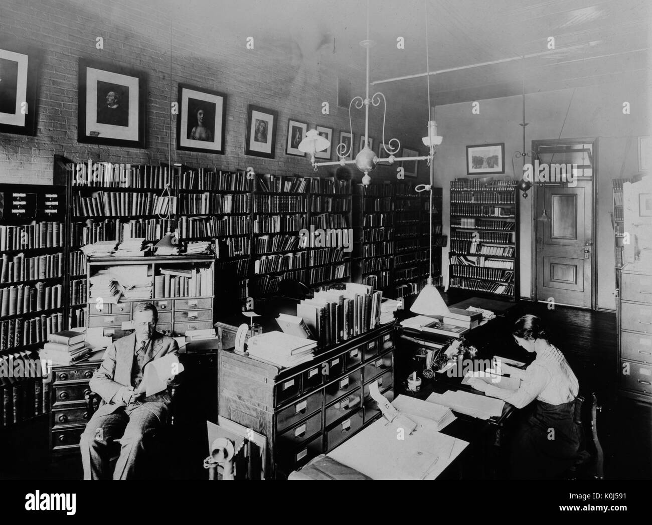 L'historien John Holladay Lataneand# 769 ; est assis à un bureau, la lecture d'une pile de papiers, dans une étagère-bureau, bordée sur l'Homewood campus de l'Université Johns Hopkins, où il a été professeur d'histoire diplomatique américaine. 1915. Banque D'Images