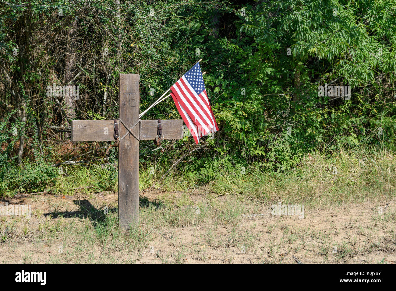 Monument commémoratif d'une mort liée à la circulation routière avec deux petits drapeaux américains et deux éperons attachés, sur une route rurale de l'Alabama. Banque D'Images