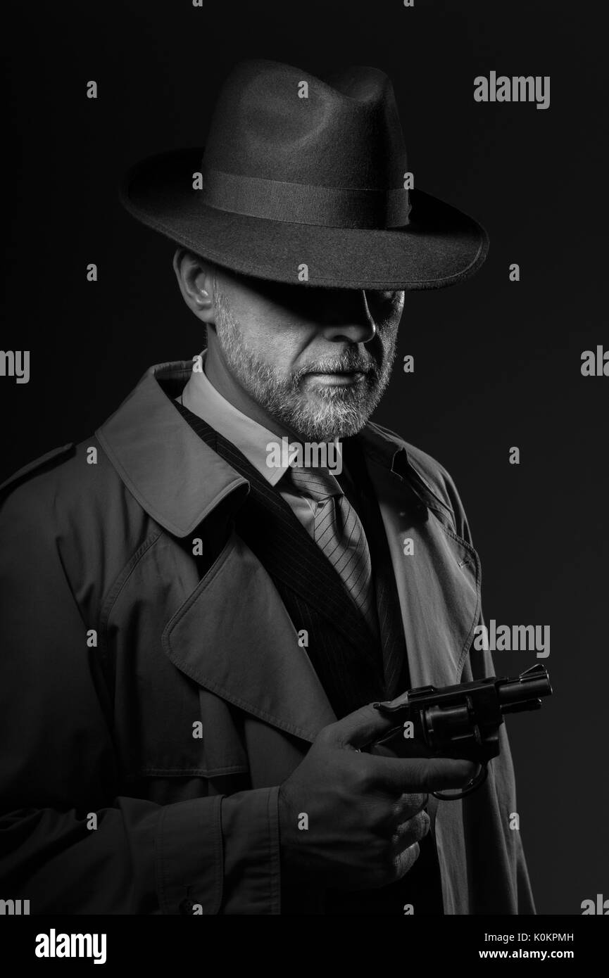 Detective tenant un pistolet, il porte un chapeau fedora et un trench coat, 1950 personnage de film noir Banque D'Images